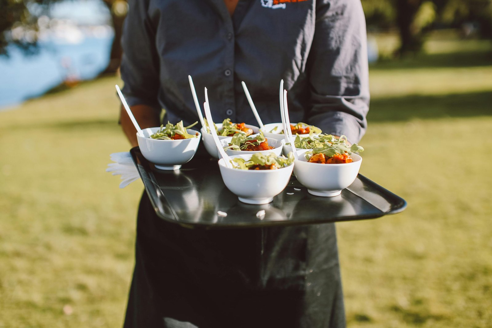 Catering service offering fresh salad bowls outdoors, featuring vibrant greens and cherry tomatoes.